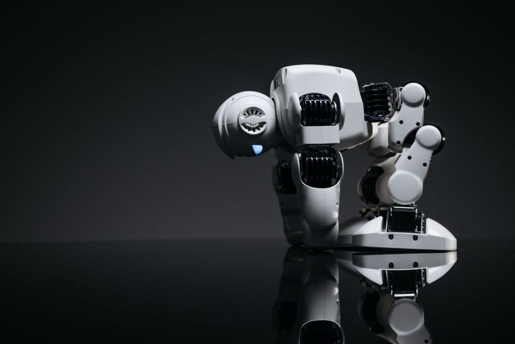 A modern robot toy depicted in a studio environment with its reflection visible on a dark surface.