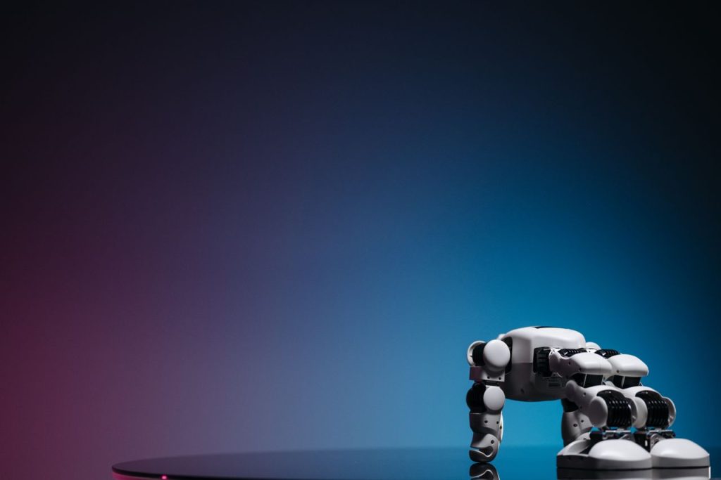 A close-up of a futuristic robot toy on a reflective surface against a gradient background.