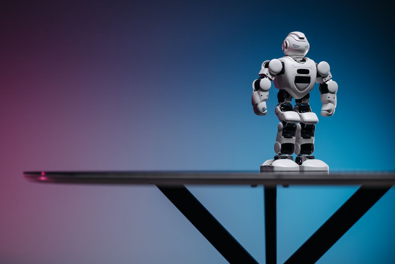 Close-up of a futuristic robot toy on a table with a gradient blue-pink background.